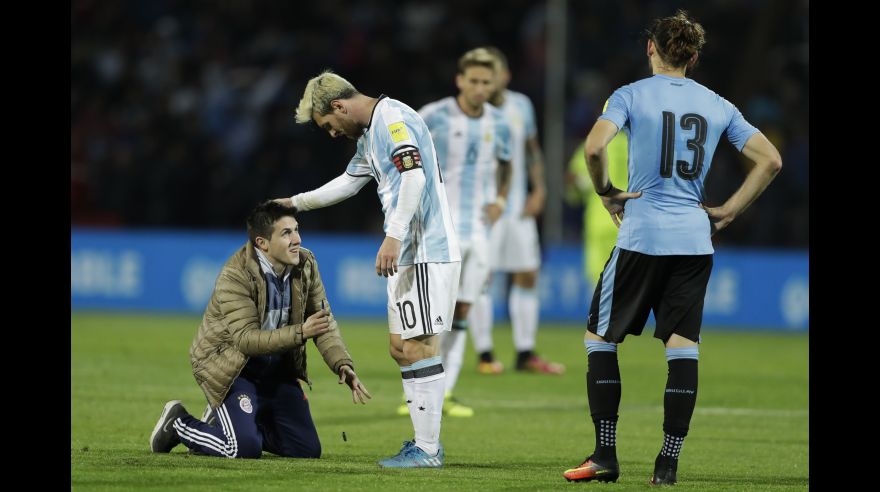 A fan who invaded the pitch kneels in front of Argentina's Lionel Messi, center, as Uruguay's Gaston Silva looks on during a 2018 Russia World Cup qualifying soccer match in Mendoza, Argentina, Thursday, Sept. 1, 2016.(AP Photo/Victor R. Caivano)
